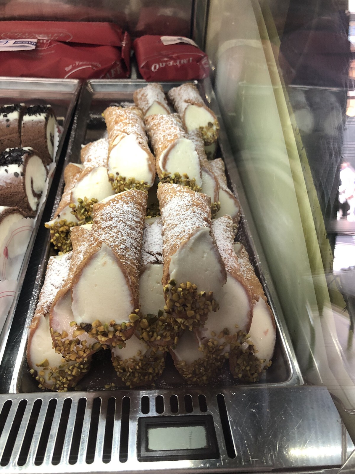 Cannoli siciliani with ricotta filling in a pasticceria window, the dessert you finish many cooking classes with