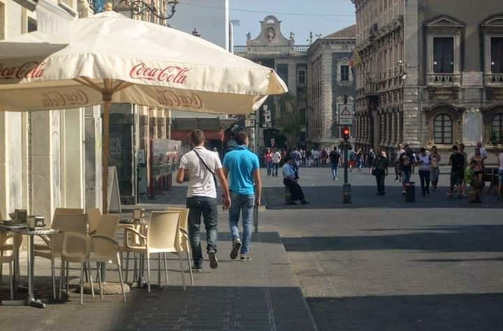 Via Etnea in Catania old town, pedestrian main boulevard framed by baroque palazzi with Mount Etna visible at the northern end