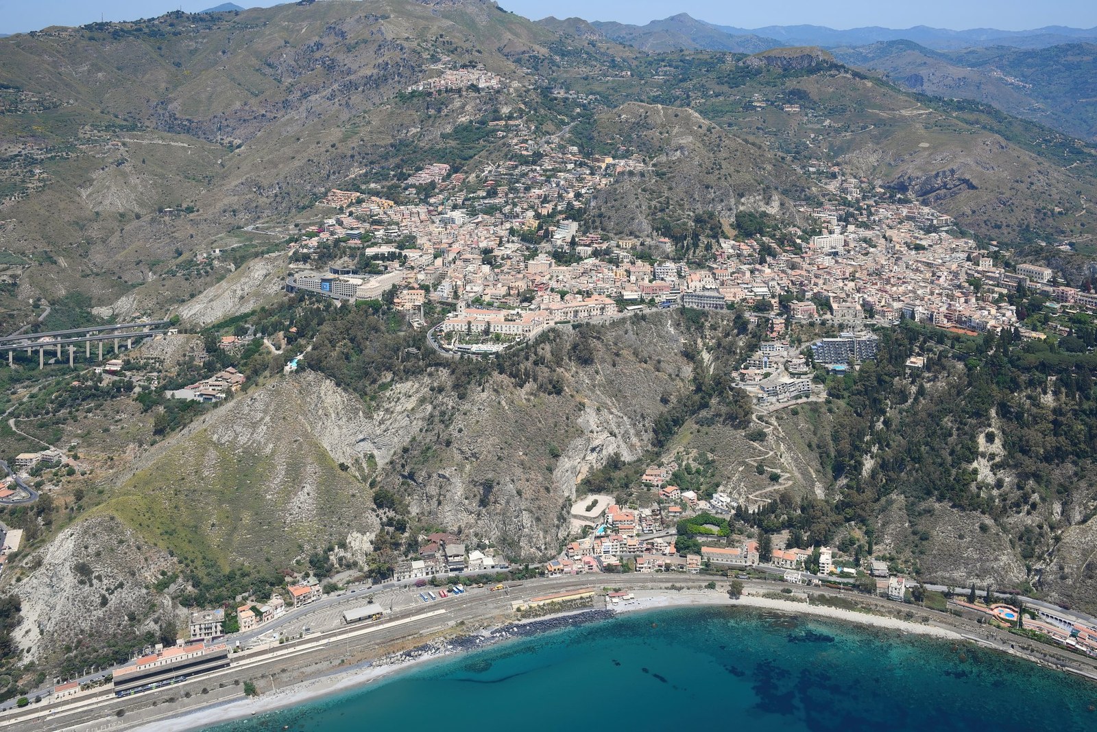 Aerial panoramic view of Taormina perched on the hillside above the Ionian coast in Sicily