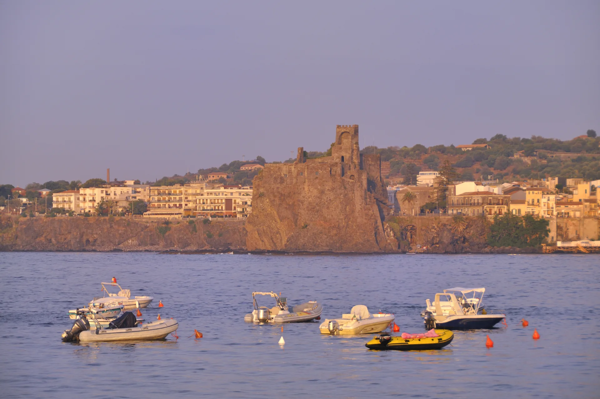 Aci Castello lungomare con il castello normanno su scoglio lavico e il mare ionico blu visti dalla costa