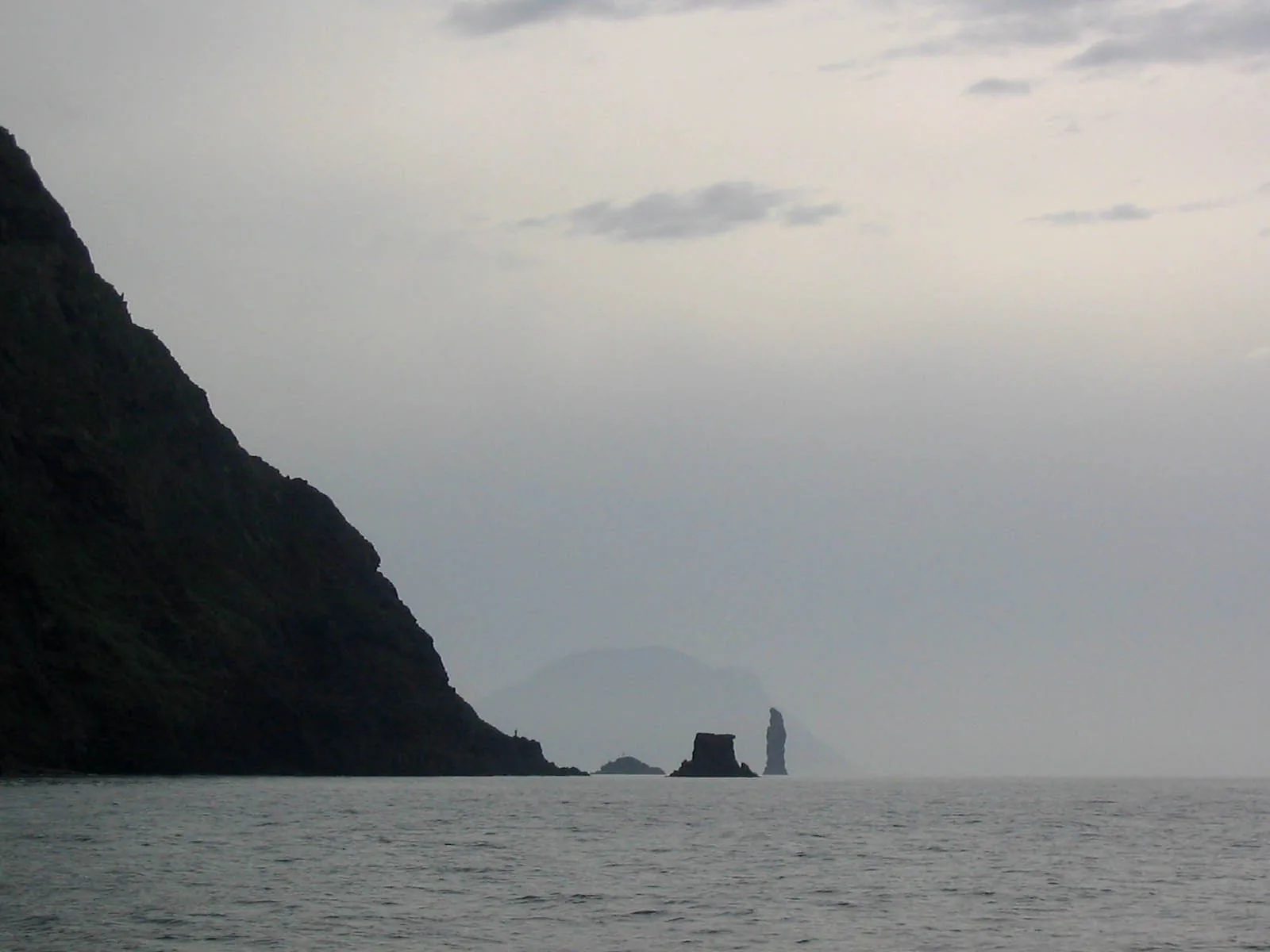 La Canna volcanic rock stack and Scoglio di Montenassari off the coast of Filicudi island, seen from the northeast with Alicudi in the background