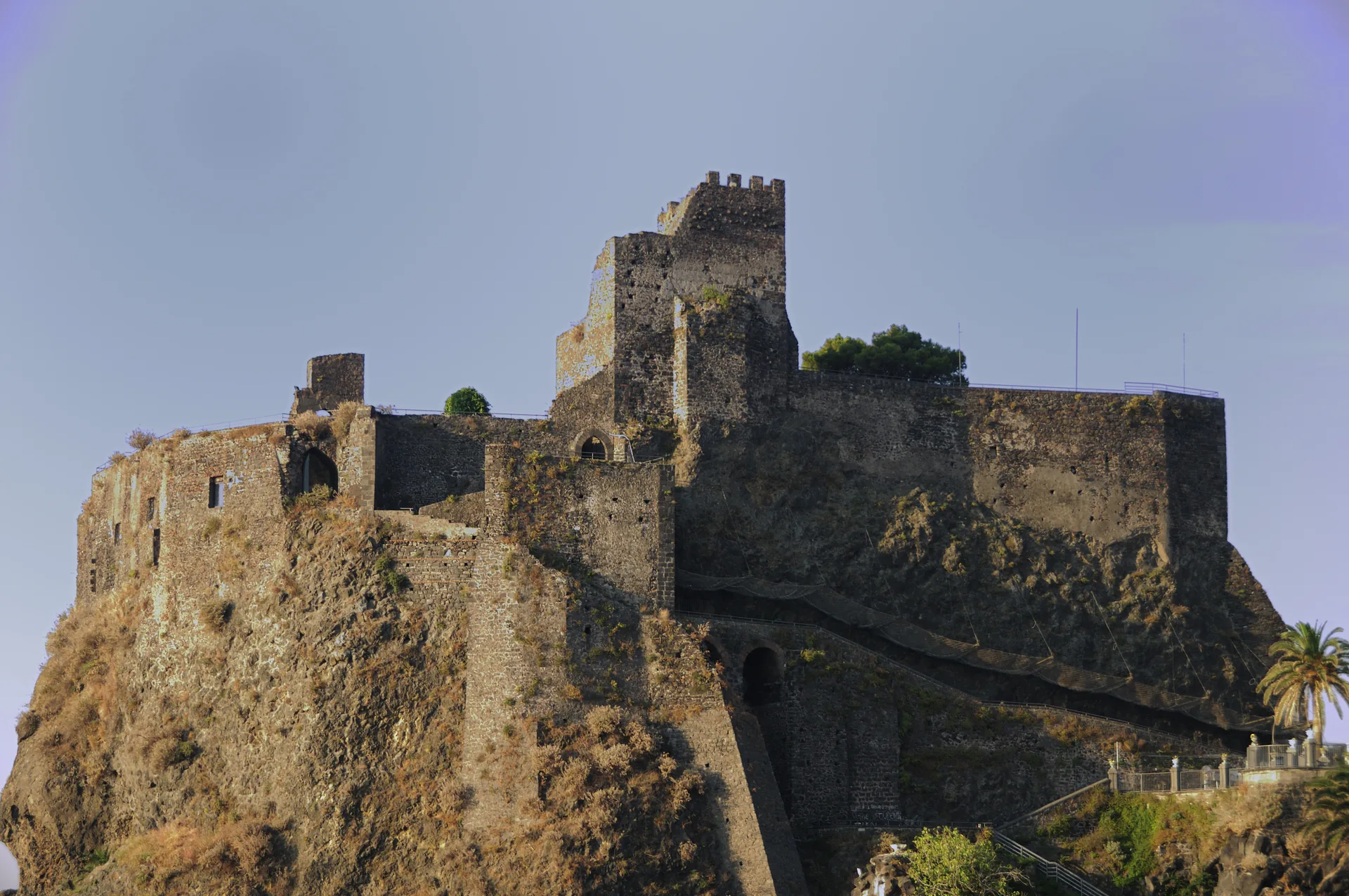 Riviera dei Ciclopi ad Aci Castello con scogliera lavica nera, lungomare e mare ionico cristallino