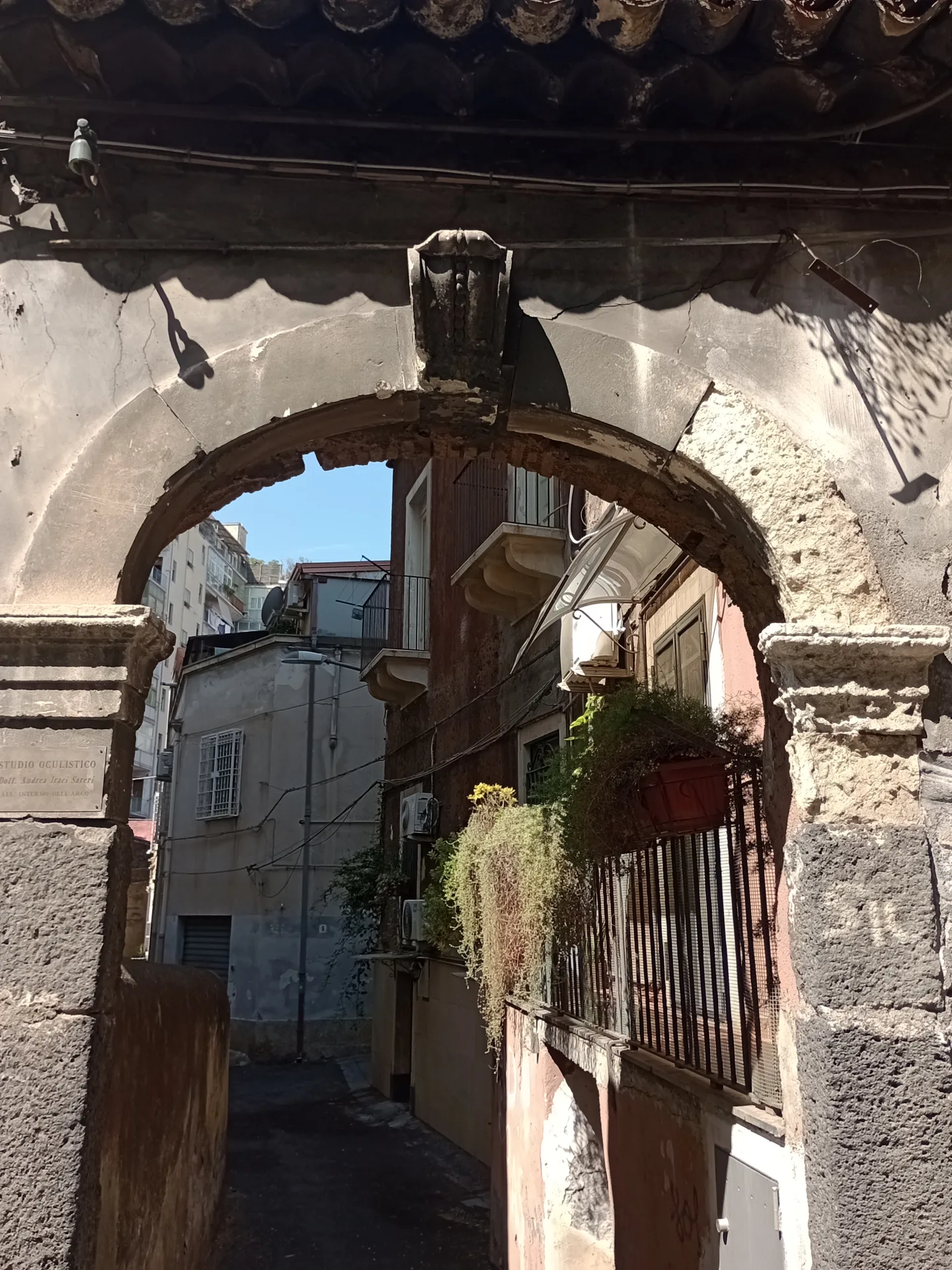 Via Etnea in the Borgo area of Catania, showing a stone archway and traditional architecture